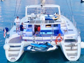 A lively scene aboard the yacht 'Pupa Mia' with guests enjoying their time, a dog on deck, and a jet ski ready for adventure — perfect for a fun day on the water.