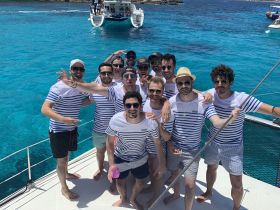 A lively group of friends celebrates aboard a yacht, enjoying the sun and vibrant turquoise waters — perfect for unforgettable summer outings.