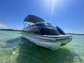 A sleek pontoon boat anchored in clear turquoise waters, perfect for leisurely days on the water.