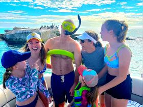 A joyful group of friends and family share a laugh on a boat, ready for a snorkeling adventure — perfect for creating unforgettable memories on the water.