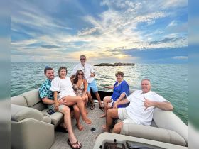 A cheerful group enjoys a sunset cruise on a pontoon boat, capturing the essence of fun and relaxation on the water.