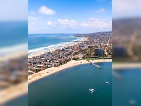 A stunning aerial view of the coastline, showcasing sandy beaches and vibrant neighborhoods along the shore — perfect for beach lovers and scenic tours.