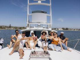 A lively group enjoys drinks and sunshine on the deck of a yacht, capturing the essence of a perfect day on the water.