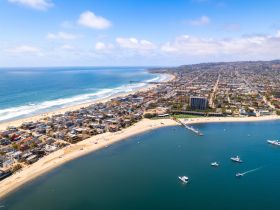 A stunning aerial view of a vibrant coastline, showcasing sandy beaches and bustling waterfront activities — perfect for beach lovers and water sports enthusiasts.