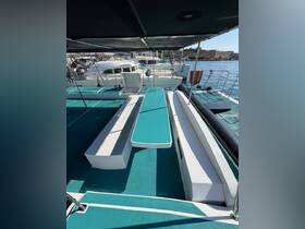 Interior view of a spacious lounge area on a catamaran, featuring comfortable seating and a vibrant turquoise deck, perfect for relaxing while enjoying the water.