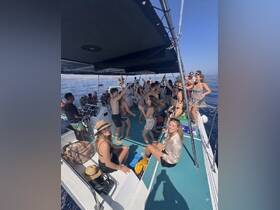A lively group enjoys a party atmosphere aboard a boat, dancing and celebrating under the sun — perfect for unforgettable summer outings.