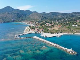 A stunning aerial view of a picturesque harbor surrounded by lush hills and clear blue waters, showcasing the beauty of the coastline.