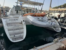 A detailed view of the 'Cicciolina Mia' catamaran docked at the marina, showcasing its sleek design and accompanying inflatable boat.