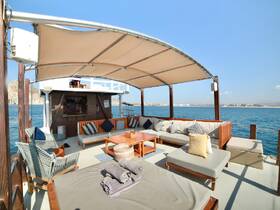 A spacious and inviting lounge area inside a boat, featuring comfortable seating and a beautiful view of the water, perfect for relaxation during a day on the sea.