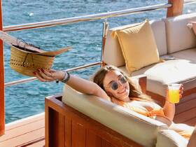 A woman enjoys a refreshing cocktail while lounging on a boat, soaking up the sun — a perfect moment of relaxation on the water.