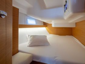 Cozy interior cabin of a boat featuring a comfortable bed and modern wooden finishes, perfect for relaxing during your nautical adventures.
