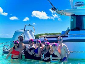 A lively group of friends enjoys a fun day in the water, celebrating with drinks beside their boat — perfect for summer outings and memorable adventures.