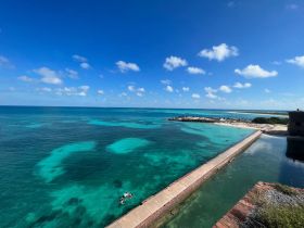 A stunning aerial view of a vibrant turquoise coastline with people swimming, showcasing the beauty of a tropical paradise.
