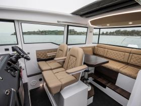 Interior view of a modern boat cabin featuring comfortable seating and a well-equipped helm, perfect for relaxing and navigating on the water.
