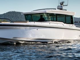 A sleek speedboat glides through the water with a driver at the helm, showcasing its modern design and performance capabilities.