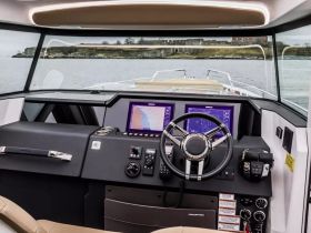 A sleek view of the helm and console inside a modern boat, showcasing advanced navigation equipment and a stylish design, perfect for a comfortable boating experience.