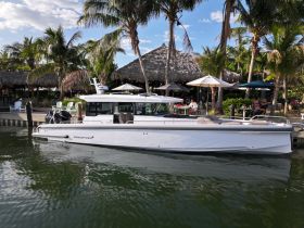 A sleek speedboat docked near a tropical setting, surrounded by palm trees and outdoor seating, perfect for a day of relaxation on the water.