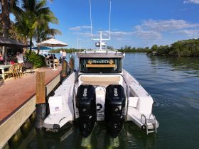A luxury boat is docked with a scenic backdrop, showcasing its sleek design and inviting atmosphere, perfect for charter experiences.