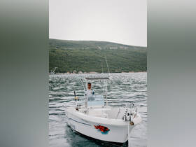 A smiling captain navigates a fishing boat through tranquil waters, showcasing the perfect setting for a day of adventure on the sea.