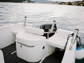 Interior view of a boat's seating area featuring comfortable white cushions and a Suzuki outboard motor, perfect for a day on the water.