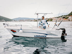 A man navigates a fishing boat in calm waters, showcasing the perfect setting for a day of fishing and adventure.