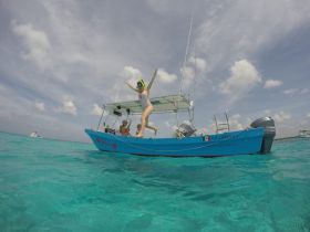 A child joyfully jumps off a boat into the vibrant turquoise waters, capturing the excitement of a snorkeling adventure with friends in a tropical paradise.