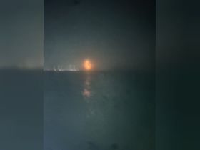 A blurry image capturing a faint orange light on the horizon, possibly a sunset or city lights, with unclear visibility.