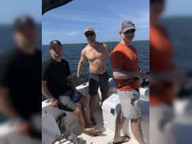 A group of friends enjoys a fishing trip on a boat, showcasing camaraderie and outdoor adventure on the water.