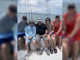 A joyful family group poses together on a fishing trip, showcasing the fun and bonding moments shared on the water.