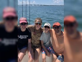 A joyful family poses together on a fishing boat, enjoying a sunny day on the water — perfect for creating lasting memories during their aquatic adventures.