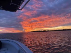 A stunning sunset view from the deck of a boat, showcasing vibrant colors reflecting on the water — perfect for serene evening cruises.