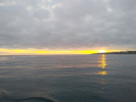 A serene sunset over calm waters, showcasing the beautiful coastline — perfect for tranquil evening boat rides.