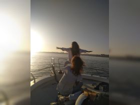 Two friends enjoy a sunset on a boat, capturing a moment of joy and freedom as they embrace the beautiful view — perfect for memorable outings on the water.