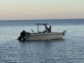 A woman stands on the deck of a boat, enjoying the serene waters at sunset — a perfect moment for relaxation and adventure on the water.