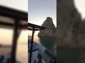 A serene view of a boat at sunset, showcasing the vessel's profile against a rocky backdrop — perfect for tranquil evening cruises.
