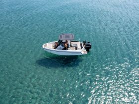 Aerial view of a sleek speedboat cruising through crystal-clear waters, perfect for enjoying sunny days on the water.