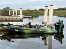 A sleek speedboat docked at a serene marina, showcasing its unique design and vibrant colors, perfect for fishing or recreational outings.