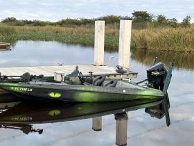 A sleek speedboat docked at a serene location, showcasing its unique design and vibrant colors against the calm waters.
