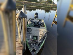 A sleek speedboat docked at the pier, showcasing its modern design and fishing gear, perfect for a day on the water.