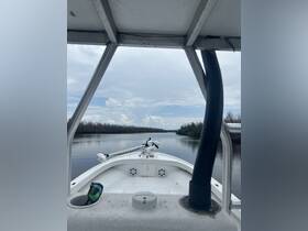 View from the helm of a boat navigating through calm waters, showcasing the interior layout and steering equipment.