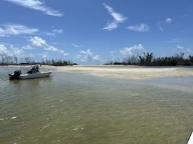 A boat navigates through shallow waters near a sandbar, showcasing a beautiful coastal landscape under a clear blue sky — perfect for exploring and enjoying nature.