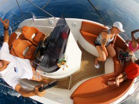 A lively group enjoys their time aboard a boat, capturing the moment with a selfie stick — perfect for fun-filled outings on the water.