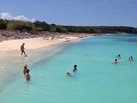 A lively group enjoys a sunny day at the beach, wading in the crystal-clear waters — perfect for a sandbar stop or family fun in the sun.