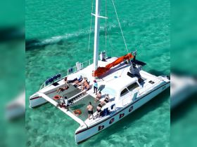 A lively group enjoys sunbathing on a catamaran in crystal-clear turquoise waters, perfect for a day of relaxation and fun on the water.