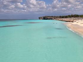 A stunning view of a serene beach with turquoise waters and rocky coastline, perfect for showcasing the natural beauty of tropical destinations.