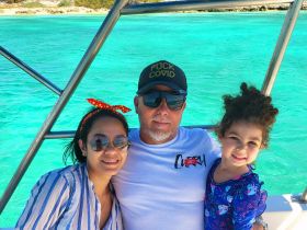 A joyful family enjoys a sunny day on a boat, surrounded by stunning turquoise waters — a perfect moment for creating lasting memories.