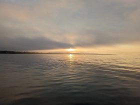 A serene sunset over calm waters, creating a picturesque reflection — perfect for tranquil boating experiences.
