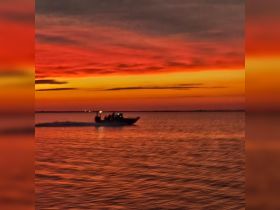 A blurred image of a boat cruising during a vibrant sunset, capturing the essence of evening adventures on the water.