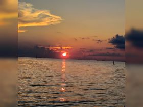 A stunning sunset over calm waters, creating a picturesque scene perfect for evening boat cruises.