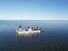 A group of anglers enjoys a day of fishing on a calm waterway, showcasing the perfect outdoor adventure on the boat.